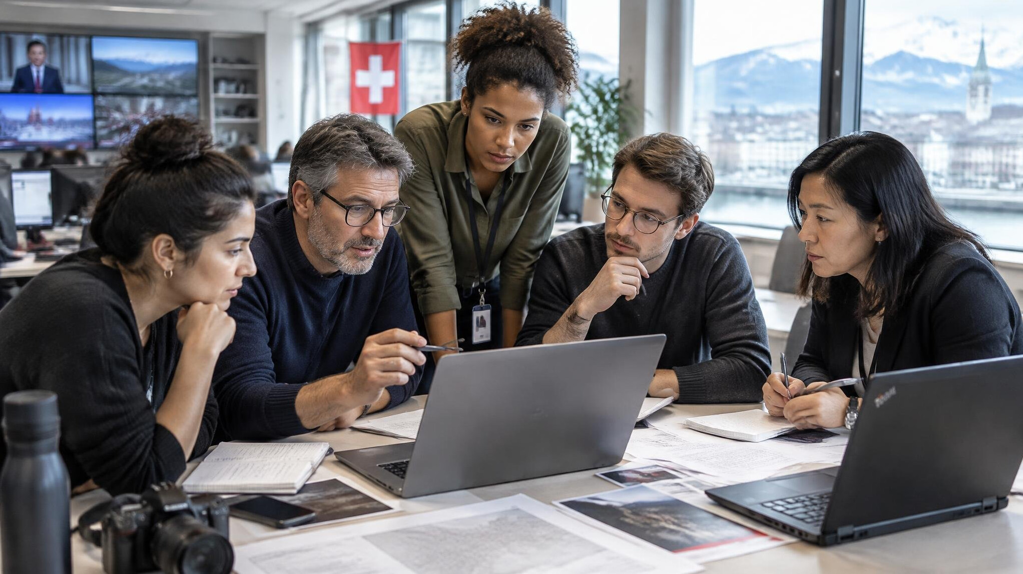 Diverse team of journalists reviewing documents and screens in a newsroom